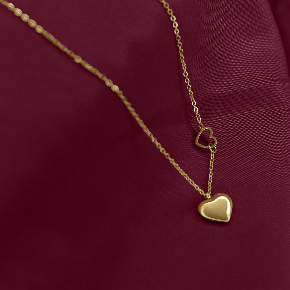 Gold necklace with heart pendants on a red fabric background